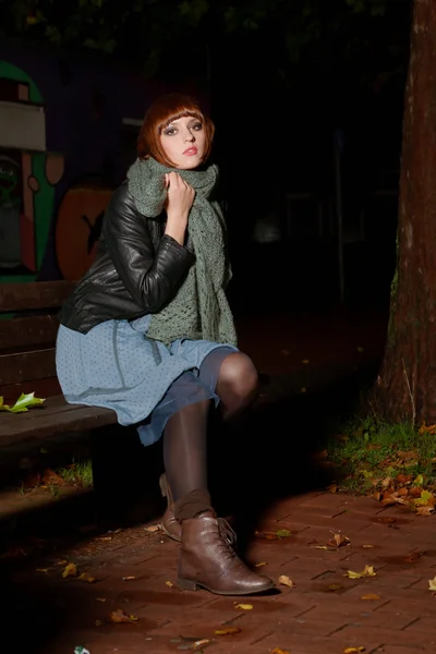 Mladá žena sedící na ulici v noci — Stock fotografie