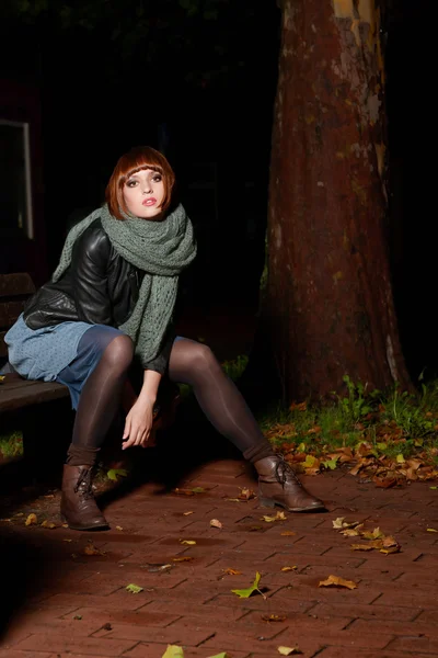 Junge Frau sitzt nachts auf der Straße — Stockfoto