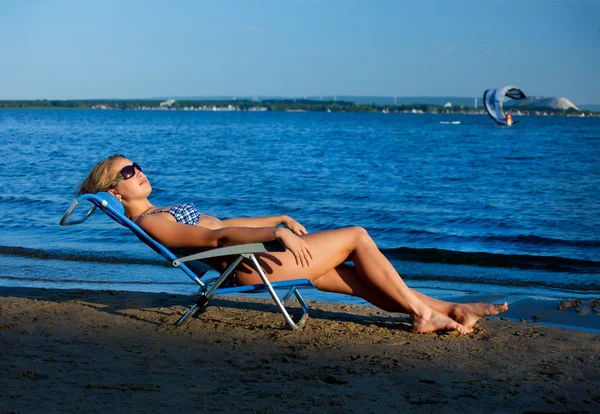 Flickan liggande på en strand i en solstol — Stockfoto