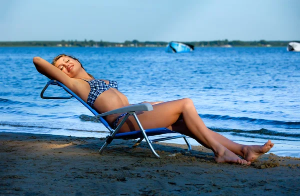 Ragazza sdraiata su una spiaggia su una sedia a sdraio — Foto Stock