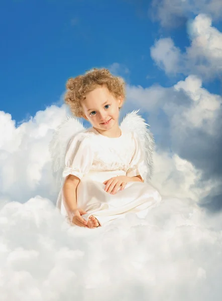 Маленькая кудрявая девочка с крыльями феи лежит на облаке — стоковое фото