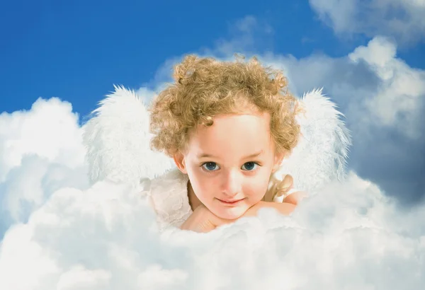 Маленька кучерява дівчинка з казковими крилами лежить на хмарі — стокове фото