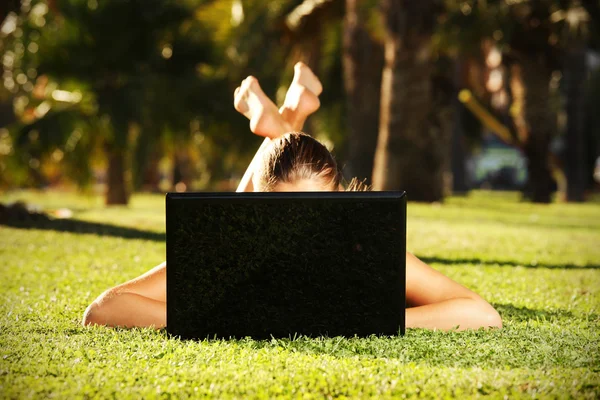 Bosá žena na trávě, schovává se za její laptop — Stock fotografie