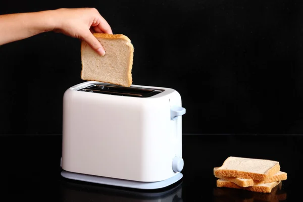 Рука кладет хлеб в тостер — стоковое фото