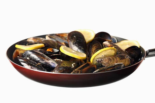 stock image A picture of a frying pan with mussels and lemon against white background