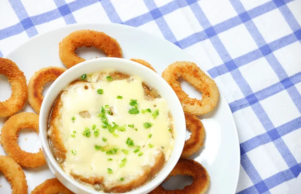 A picture of a bowl of fresh french onion soup baked with toast and cheese and onion rings