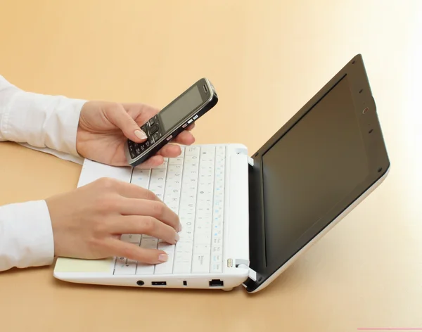 Mãos femininas e laptop com celular — Fotografia de Stock