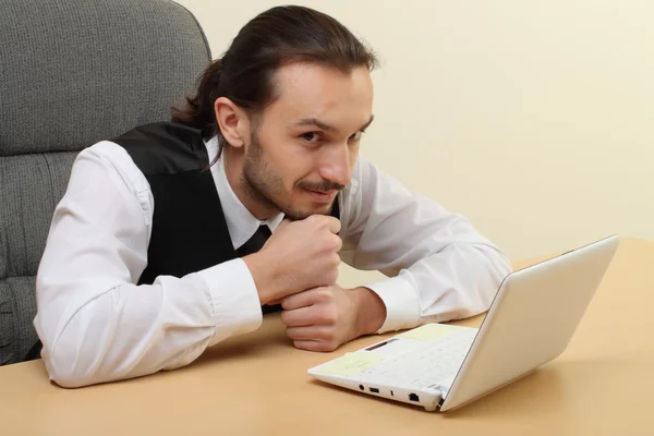 Человек думает на рабочем месте перед ноутбуком — стоковое фото