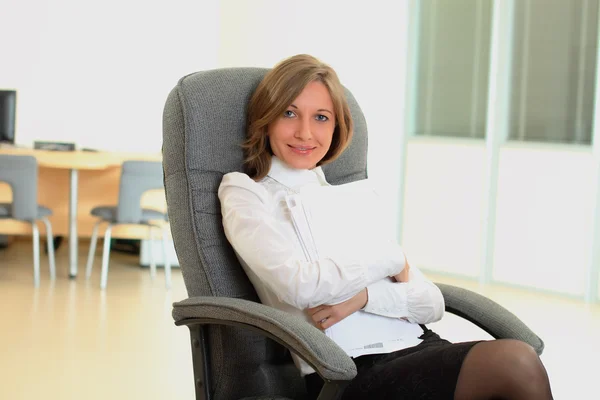 Frau sitzt auf Stuhl und hält Papiere mit Stift in der Hand — Stockfoto