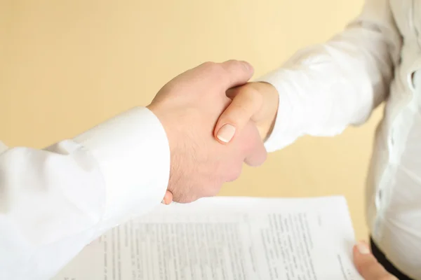Man and woman shaking hands in office and giving papers — Stock Photo, Image