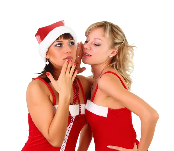 Девушки в рождественском платье Санты шепчутся Стоковая Картинка