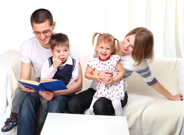 Ευτυχισμένη οικογένεια, διαβάζοντας ένα βιβλίο στον καναπέ — Φωτογραφία Αρχείου