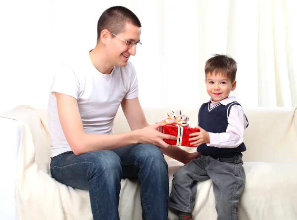Pai dá presente para seu filho em caixa vermelha em casa — Fotografia de Stock