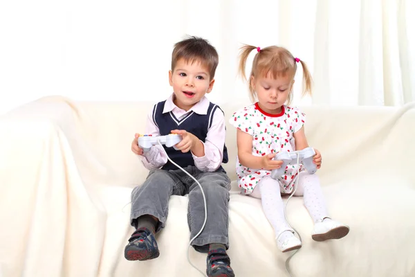 stock image Little boy and girl playing tv game on sofa