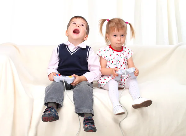 stock image Little boy and girl playing tv game on sofa