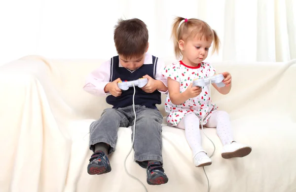 stock image Little boy and girl playing tv game on sofa