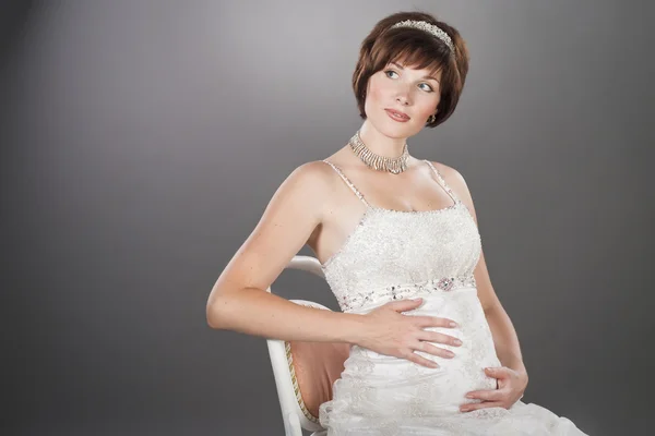 Портрет красивой беременной женщины, сидящей на стуле — стоковое фото
