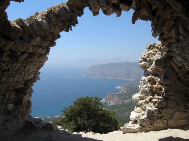 Rhodes island coast through wall opening of Monolithos castle ruins. Greece. clipart