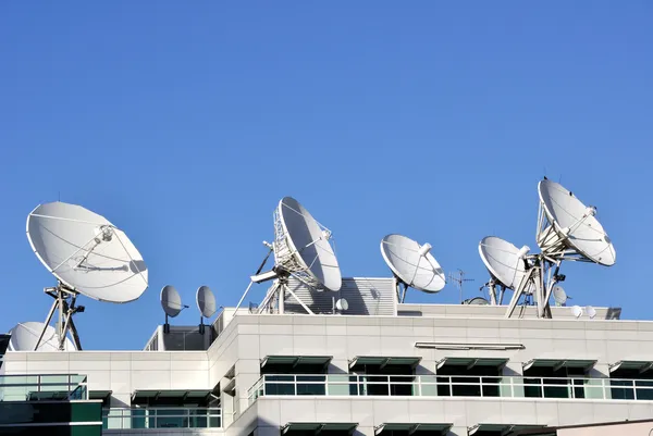 Piatti di comunicazione satellitare in cima alla stazione TV Foto Stock
