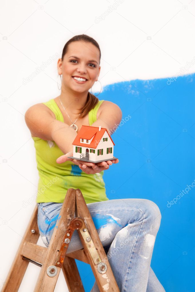 Smiling repair woman at the ladder with a miniature house
