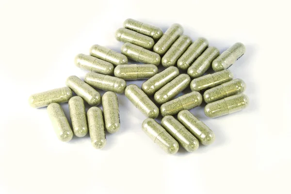 Капсула зеленой травяной медицины на белом фоне — стоковое фото