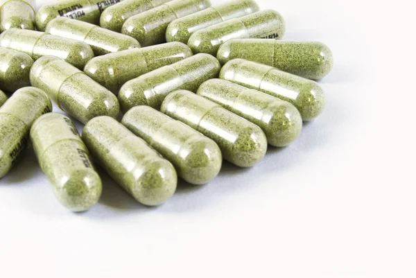 Капсула зеленой травяной медицины на белом фоне — стоковое фото