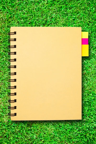 在绿色草地上的小笔记本 — 图库照片