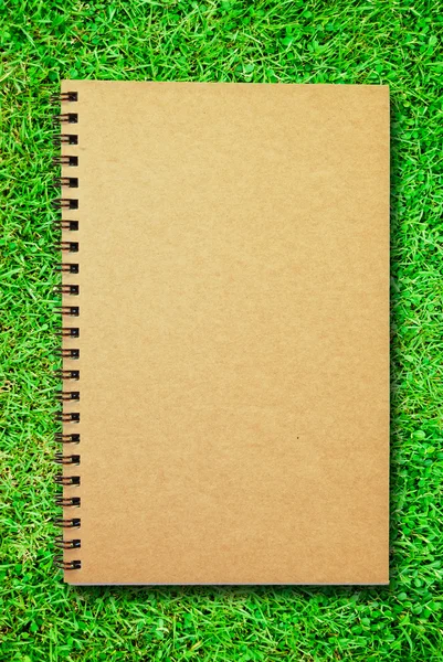 Caderno de capa marrom no campo de grama verde — Fotografia de Stock