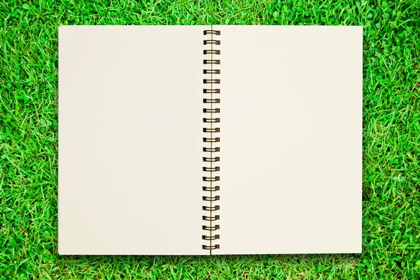 Notebook em branco aberto no campo de grama verde — Fotografia de Stock
