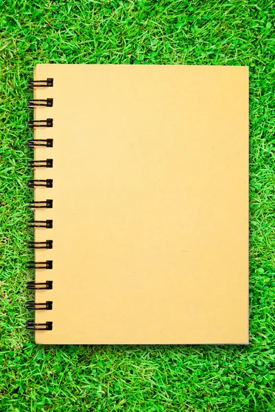 Small notebook on green grass field — Stock Photo, Image