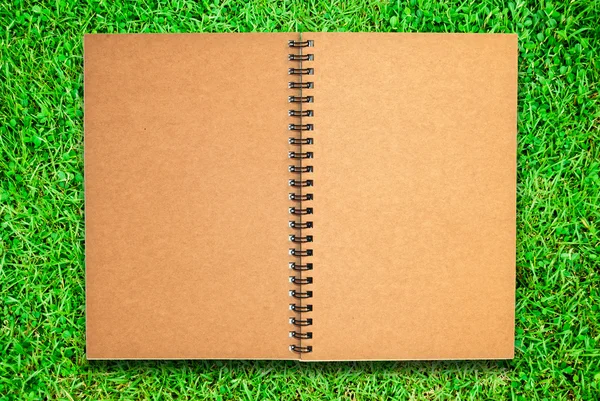 Brown recycle paper notebook open on green grass field — Stock Photo, Image
