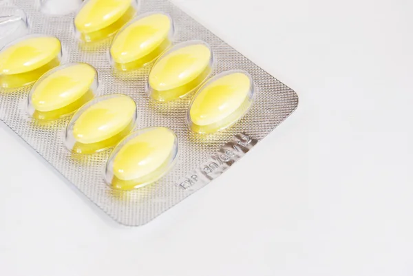 Embalagem de comprimidos de medicamentos amarelos no fundo branco — Fotografia de Stock