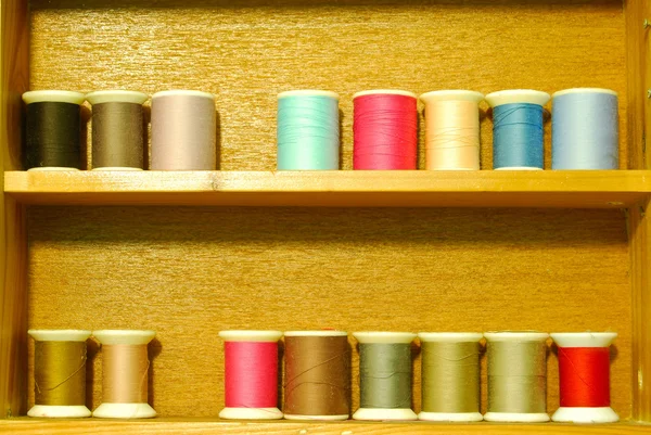 Kolorowe szpulę wątku na drewniane półki — Zdjęcie stockowe