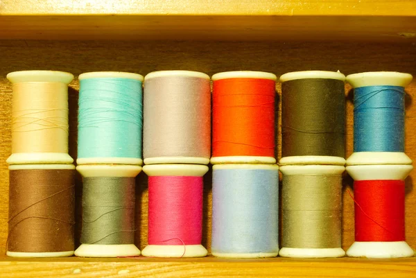 Colorful spool of thread on wood shelf — Stock Photo, Image