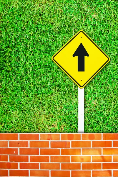 Go ahead traffic sign on brick wall and grass — Stock Photo, Image