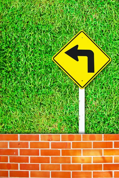Turn right traffic sign on brick wall and grass field — Stock Photo, Image