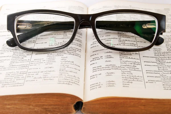 Closeup of old dictionary and glasses — Stock Photo, Image