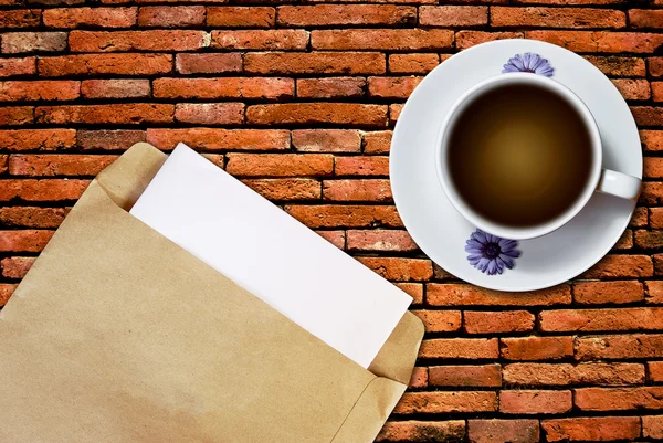 白喝杯咖啡和棕色信封文档砖背景墙上 — 图库照片