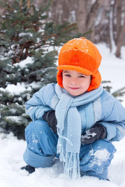 Kleine jongen spelen sneeuwballen; sneeuwpop beeldhouwt; graaft sneeuw; Stockafbeelding
