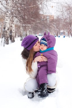 öpüşme ve bir bebek, snow, winter park, tutan annesi yürümek