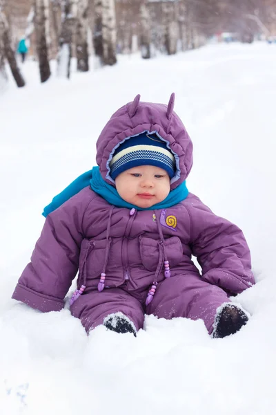 A little boy, baby sits in the snow, snowball — Stock Photo, Image
