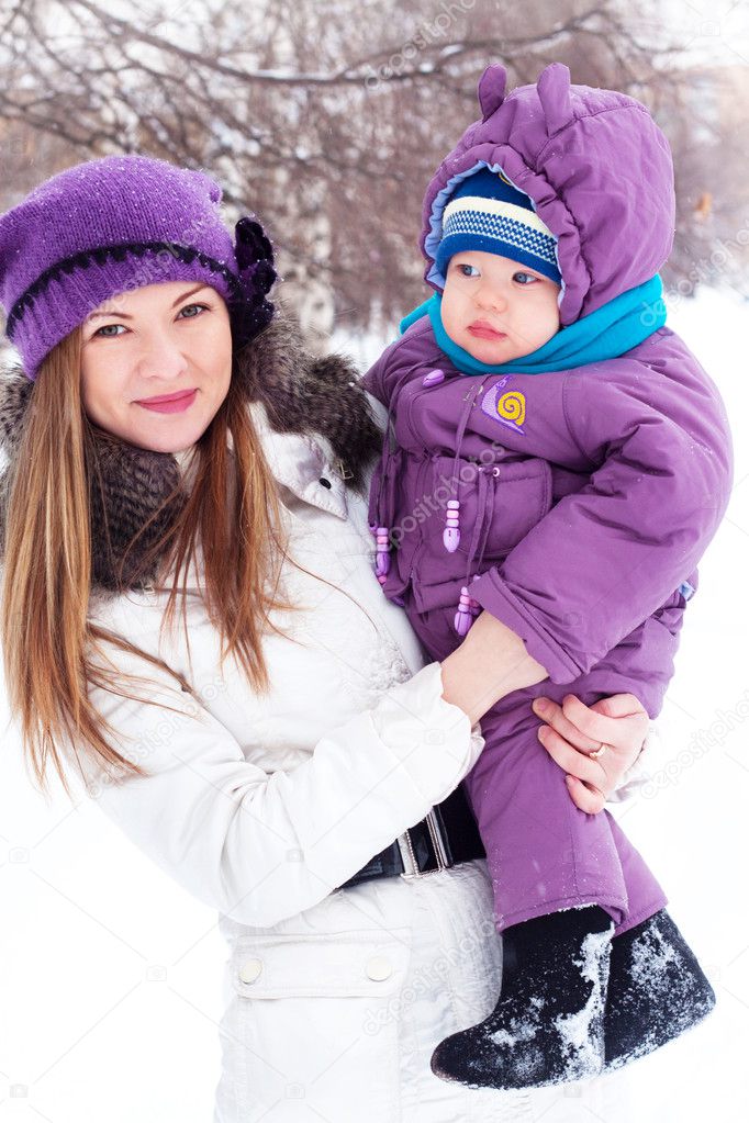 Mother holding a baby, snow, winter park, walk