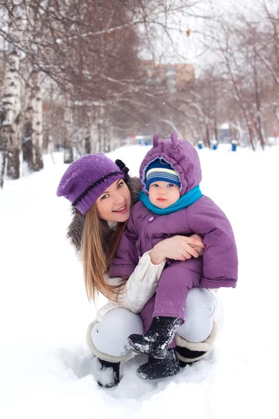 Madre sosteniendo un bebé, nieve, parque de invierno, caminar —  Fotos de Stock