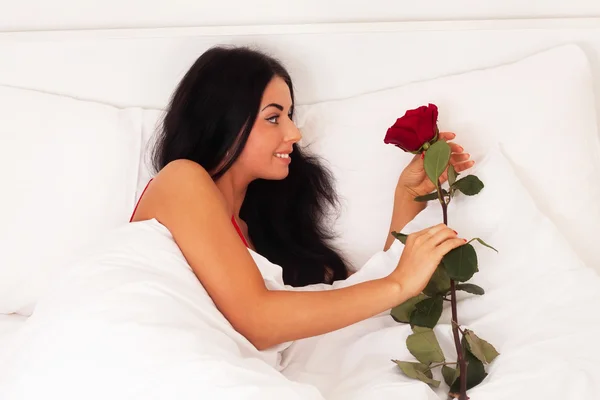 Young girl lying in bed with gifts, roses, woke up — Stock Photo, Image