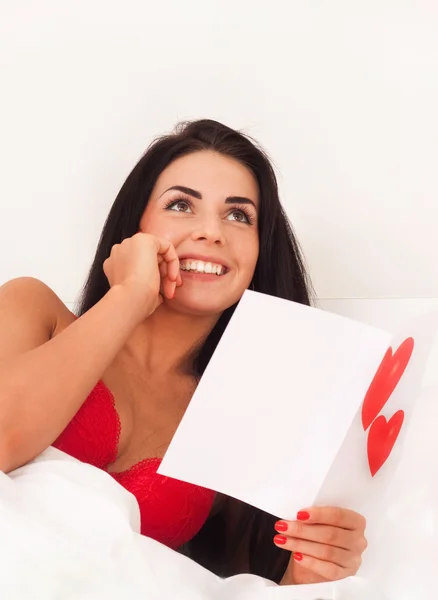 Chica joven acostada en la cama con regalos, tarjetas, corazones —  Fotos de Stock