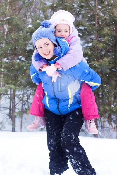 stock image Happy mother and daughter, the family for a walk in a winter park, luge, skiing, skating, snowballs