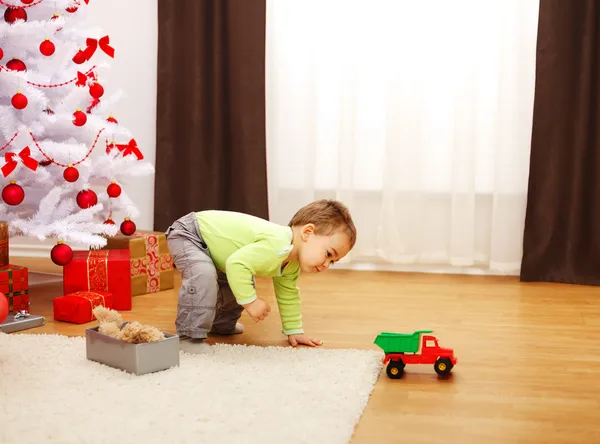 Liten pojke i jul, leker med nya leksaksbil — Stockfoto