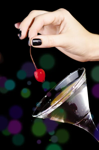 La mano poniendo la cereza roja a la copa de martini — Foto de Stock