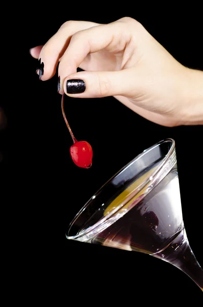 把红樱桃放到马提尼酒杯的手 — 图库照片