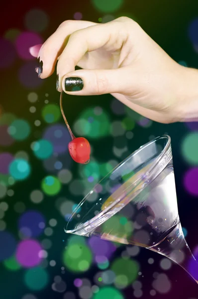 Die Hand, die die rote Kirsche auf das Martini-Glas legt — Stockfoto